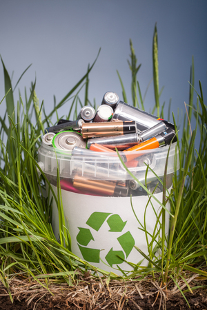 Battery recycle bin with old element on wood table in grassの写真素材