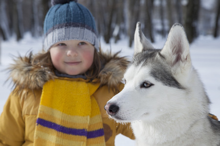 happy boy playing with dog or husky outdoors in winter day.の写真素材