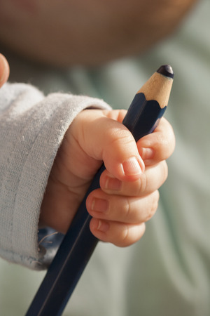 Black big pencil in the hand of the baby childの写真素材