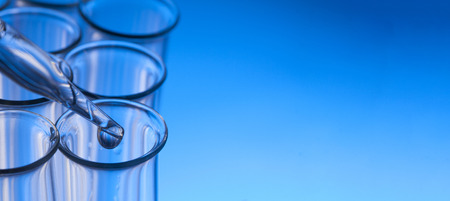 glass test tube with dropper on blue background with substance.