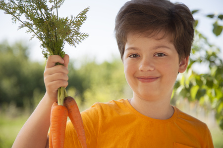 Happy boy biting the carrot, A child with a vegetable. Kid eating fresh carrotsの写真素材