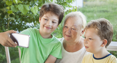 Grandmother and Grandchildren do Selfie in the summer garden. Family generation children and senior old people communication.の写真素材