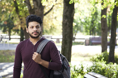 student teenage boy walks to study in green park.