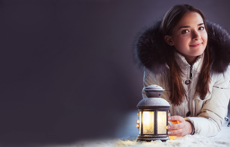 beautiful girl on winter snow with christmas lantern.の写真素材