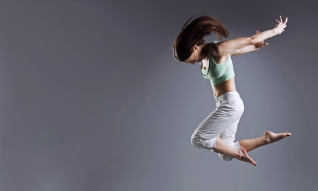 Woman jump. Beauty girl dance on grey background.の写真素材