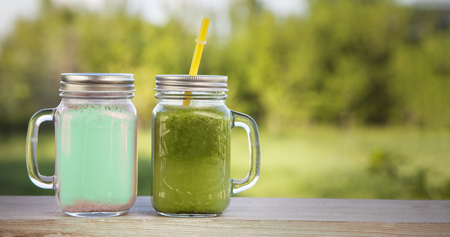 glass of detox smoothie on wooden table in the summer garden with fruit.の写真素材