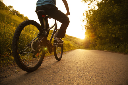teenager riding a bicycle on the road summer sunlit, bike ride