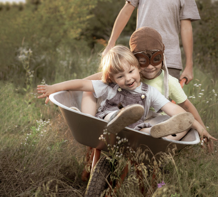 two friends playing in the plane using a garden cartsの写真素材