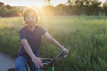teenager riding a bicycle on the road summer sunlit, bike rideの写真素材