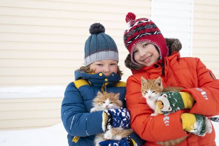 two boys plays with a cat outdoors in winterの写真素材