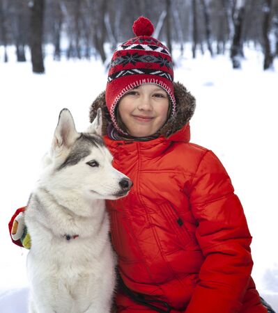 happy teenager boy playing with white Husky dog in winter day, pet and child on snowの写真素材