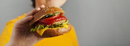 Burger in hand on grey background. Big hamburger.の写真素材