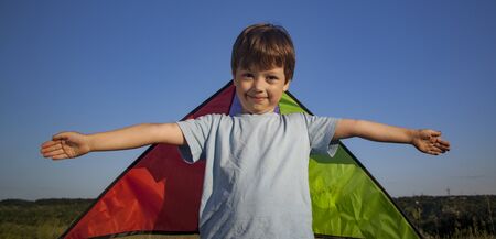 Children run with kite on summer sunset meadow. playing outdoorsの写真素材