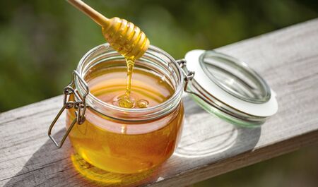 Honey in glass jar on a wooden floor.
