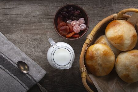 Hot cross buns on wooden table served with milk and dried fruit, jug of cream.の写真素材