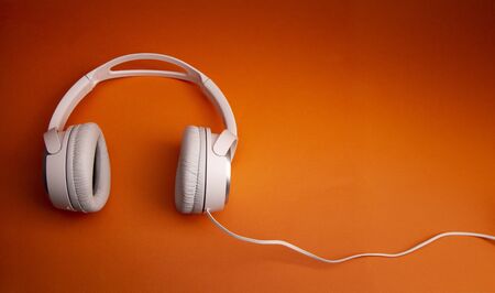 White wireless headphone on orange background.の写真素材