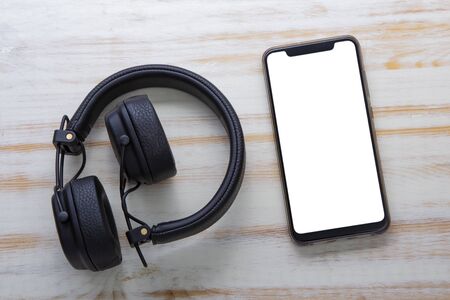 Modern Headphones with Smartphone on wood background, Music online concept, top view, mockupの写真素材