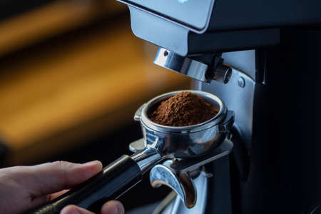 coffee grinder grinding coffee pouring into a portafilterの写真素材