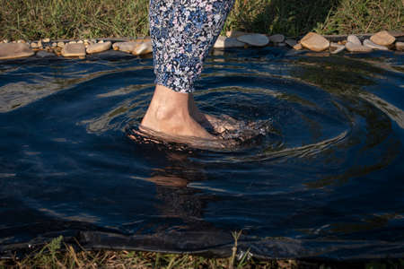 Woman foot splashing water in a puddle on a rainy dayの写真素材