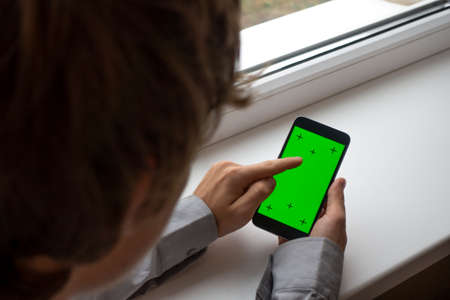 hand holding the black smartphone green screen with modern designの写真素材