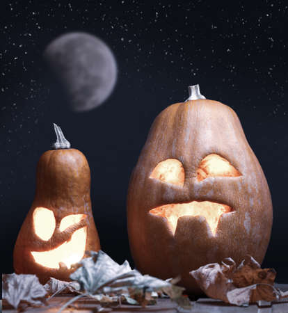 Jack o lanterns Halloween pumpkin face on night stars and moon background and autumn leafsの写真素材