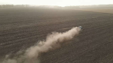 Modern tractor working plowing and sowing on the agricultural field - aerial view - high top view