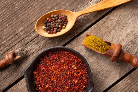 A set of spices and herbs. Indian cuisine. Pepper, salt, paprika, basil, turmeric. On a black wooden background. Top view.の写真素材