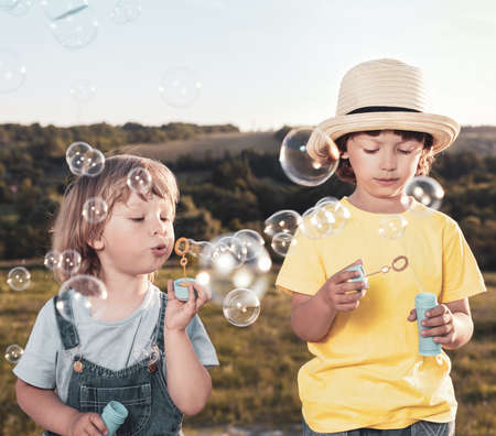 Happy Boy play in bubbles in field sunny summer day.
