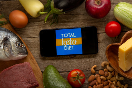 Total Keto Carb Manager app for diet calorie counter on smartphone. Diet Plan On Tablet Pc And Vegetables. Belgorod , Russia - AUG, 18, 2020:のeditorial素材