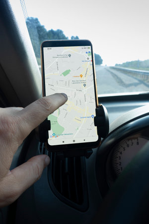 Hand with a smartphone in the car. Looking at phone Google Maps Navigator. Google is the biggest Internet search engine in the world. Belgorod, Russia - JUN, 13, 2020:のeditorial素材