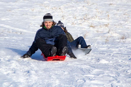 boy sliding down snow hill on sled outdoors in winter, sledging and season concept