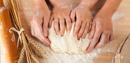 children's hands and the hands of his mother and knead the dough togetherの写真素材