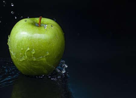 Green apple in Water splashing stream on on Black background