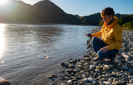 The teenager boy on mountain river beachの写真素材