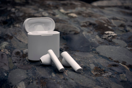 Wireless earphones, earbuds on a dark stone background.の写真素材