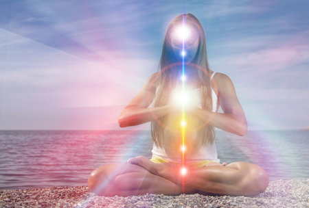 Yoga meditation outdoors. Glowing seven all chakra. Woman sits in a Upward Salute pose on beach...
