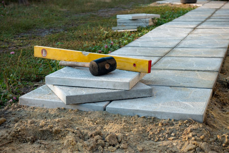 Laying a paving stone or brick. Gray concrete slabs in house courtyard on sand foundation base.