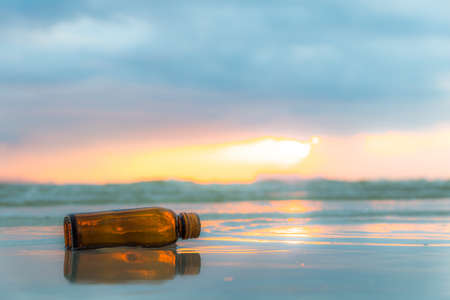 Glass bottle on tropical sea beach at sunset.の写真素材