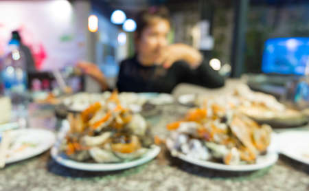 Blurred background : Woman is eating seafood at restaurant.の写真素材