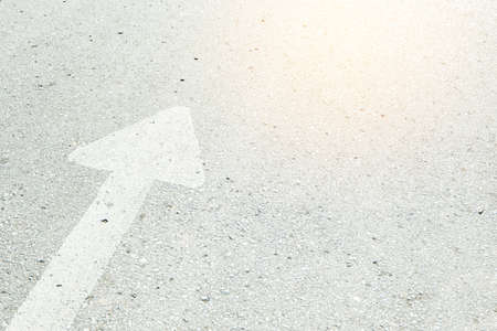 Forward white arrow sign on gray asphalt road.の写真素材