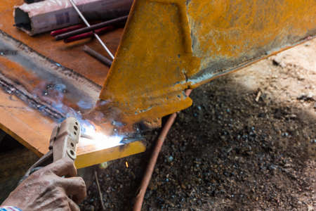 Worker welding the iron for fix wheel loader.