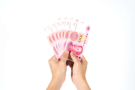 Hand holding Chinese yuan banknotes on white background. Close up human hand giving and paying China money (rmb or renminbi)の写真素材