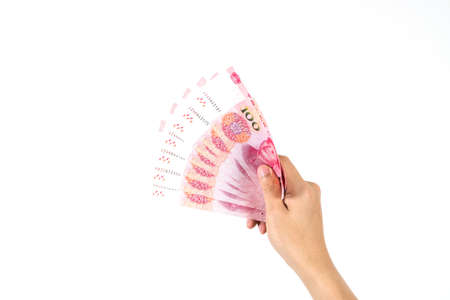 Hand holding Chinese yuan banknotes on white background. Close up human hand giving and paying China money (rmb or renminbi)の写真素材