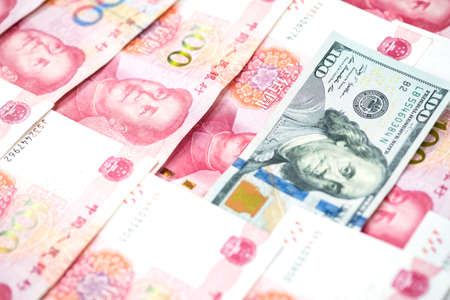 Different concept with one hundred US dollar bill in pile of one hundred Chinese yuan bills,...