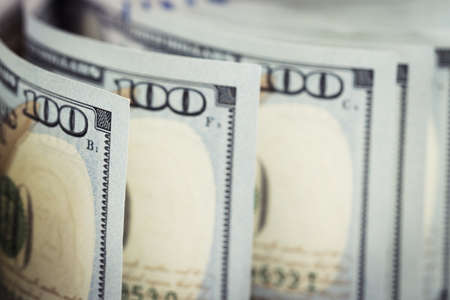 Several pile of new one hundred us dollar bills on table. Close up and selective focus on curved one hundred dollar banknotes as money background. Financial and currencies concept.の写真素材