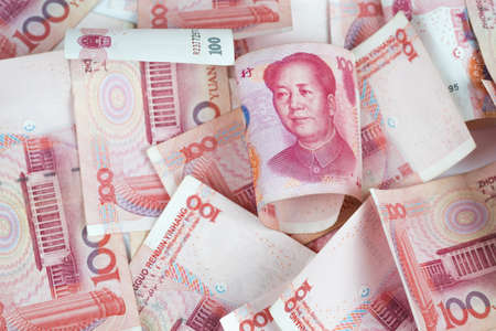 Closeup Chinese yuan bills on table. Yuan is the currency of China, Selective focus on stack of one hundred Chinese yuan banknotes for money background in tone.の写真素材