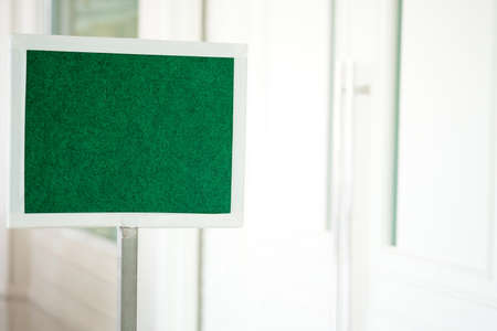 Blank green synthetic fabric billboard or banner standing in front of meeting room used to inform room usage to others in modern hotel.の写真素材