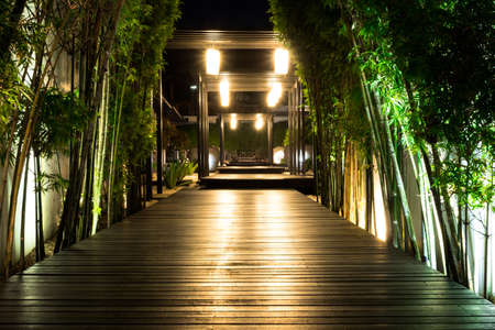 Soft focus of black wooden garden path with bamboo on both side at night, Garden decorative lighting.の写真素材