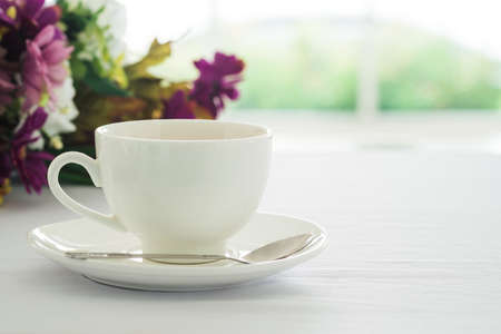 Cup of black coffee placed on white table flower and blurry garden background at coffee shop in morning.の写真素材