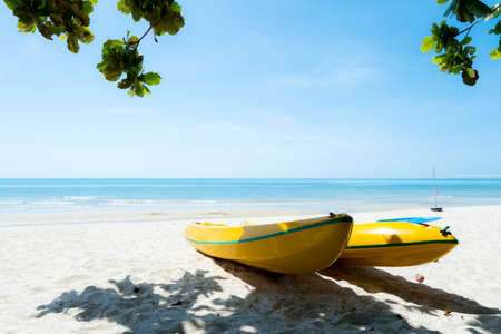 Yellow kayak boats on summer beach in bright morning over tropical blue sea background.の写真素材